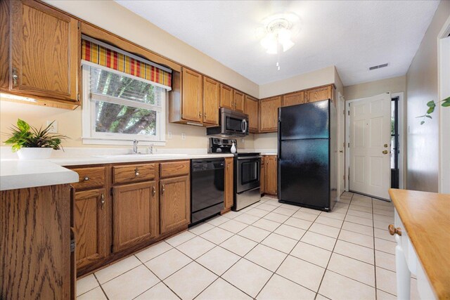 8570 W Park Trail Dr, Germantown, TN 38139 - kitchen featuring black appliances, a sink, brown cabinets, light countertops, and light tile patterned floors