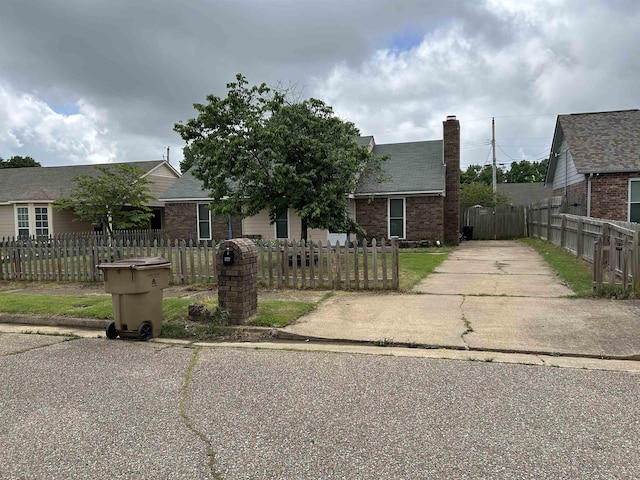 6823 Northknoll Ave, Millington, TN 38053 - view of front facade featuring brick siding, driveway, a chimney, a fenced front yard, and roof with shingles