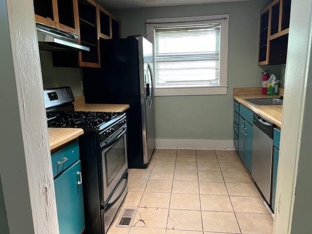 1917 Walker Ave, Memphis, TN 38104 - kitchen featuring appliances with stainless steel finishes, exhaust hood, a sink, light tile patterned floors, and blue cabinets