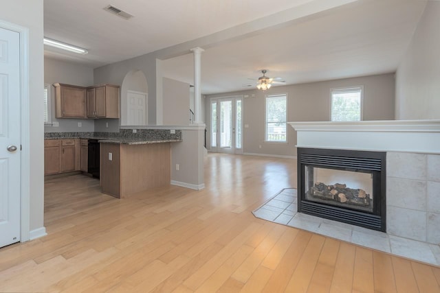 kitchen featuring a multi sided fireplace, ceiling fan, light wood-style flooring, open floor plan, and baseboards