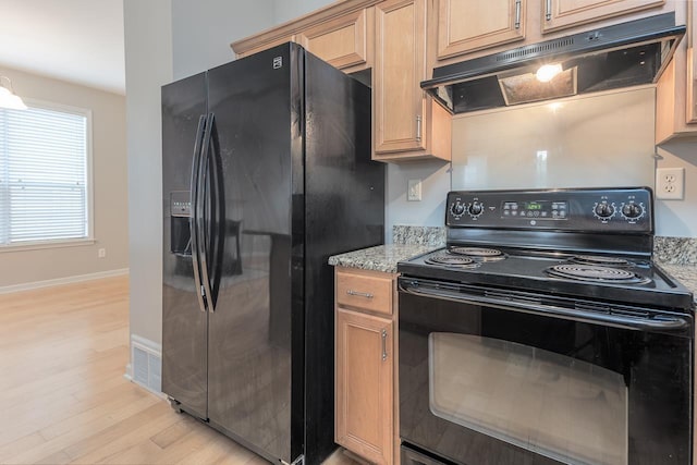 kitchen with black appliances, under cabinet range hood, light wood-type flooring, baseboards, and light stone countertops