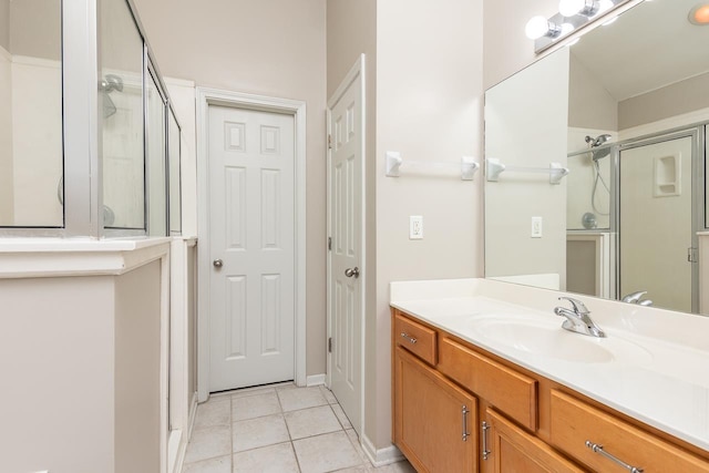 full bathroom with a stall shower, tile patterned flooring, vanity, and baseboards