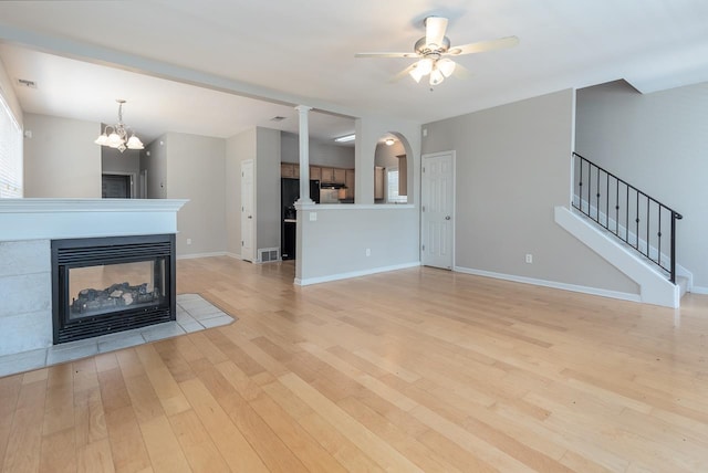 unfurnished living room with light wood finished floors, a ceiling fan, baseboards, stairway, and a multi sided fireplace