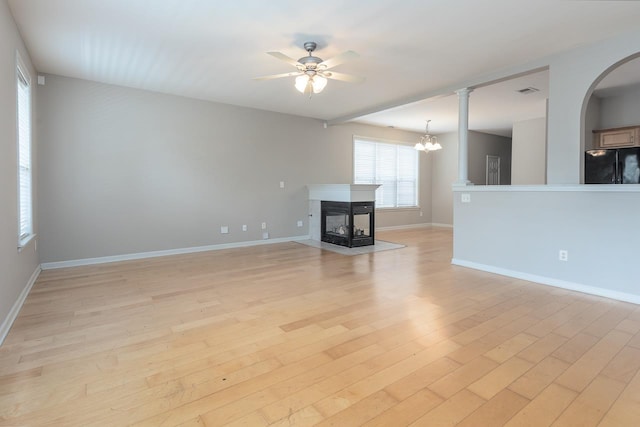 unfurnished living room featuring light wood-style flooring, a ceiling fan, a multi sided fireplace, and baseboards