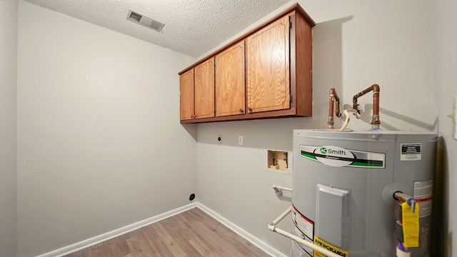 979 Ray Bluff Rd, Millington, TN 38053 - washroom with electric dryer hookup, water heater, cabinet space, light wood-style flooring, and a textured ceiling