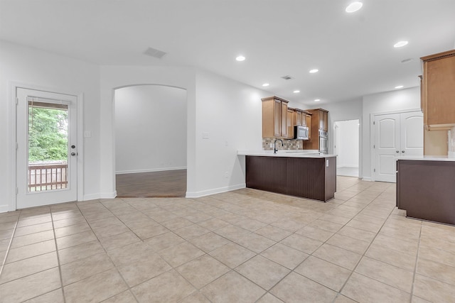 1235 Gimel Ln, Cordova, TN 38016 - kitchen with stainless steel microwave, light countertops, a peninsula, recessed lighting, and arched walkways