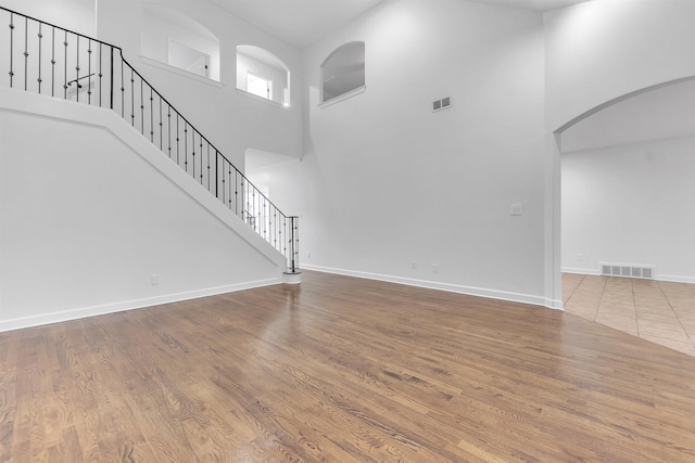 1235 Gimel Ln, Cordova, TN 38016 - unfurnished living room featuring a high ceiling, wood finished floors, baseboards, arched walkways, and stairway