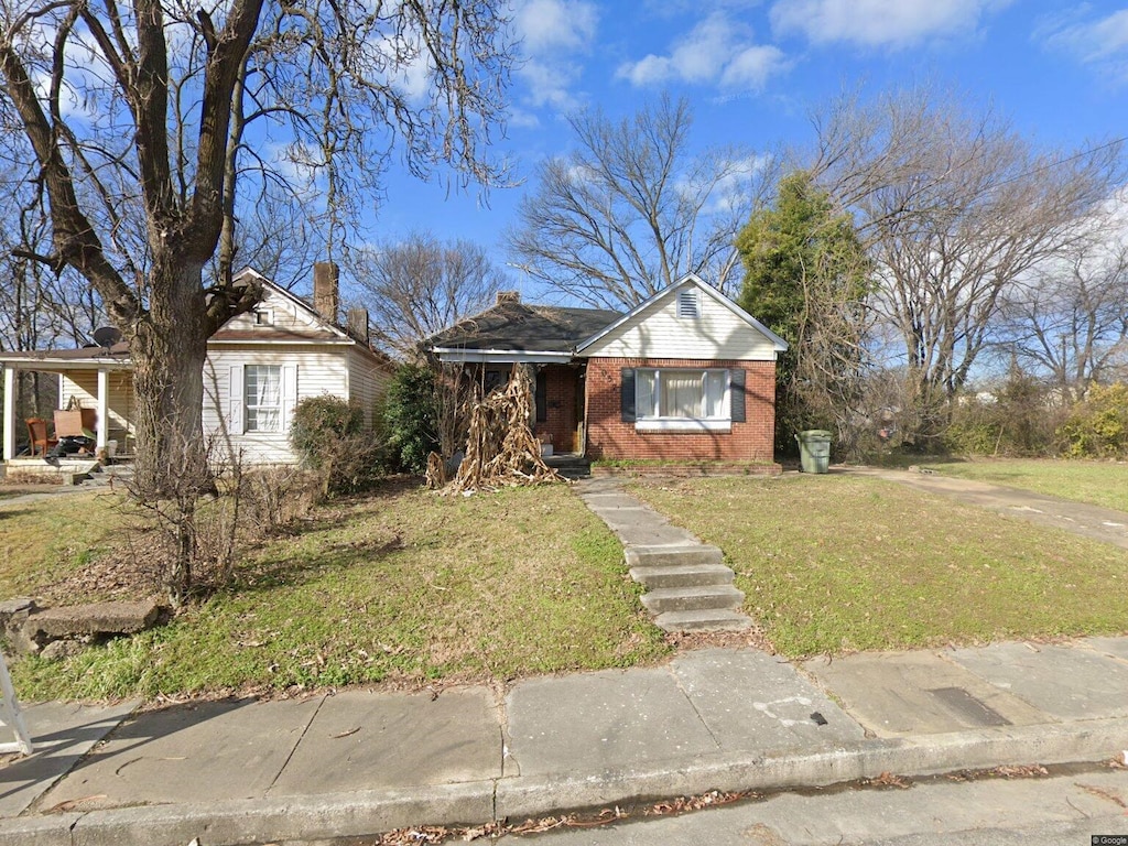 1057 Walk Pl, Memphis, TN 38106 - view of front facade with brick siding, a front yard, and a chimney
