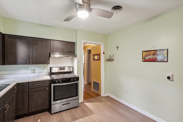 4381 Embassy Dr, Memphis, TN 38108 - kitchen with stainless steel gas range oven, light wood-type flooring, dark brown cabinetry, ceiling fan, and under cabinet range hood