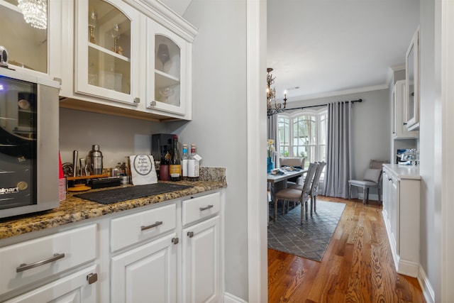 215 Ivy Grove Ln, Collierville, TN 38017 - kitchen featuring a chandelier, wood finished floors, glass insert cabinets, white cabinets, and ornamental molding