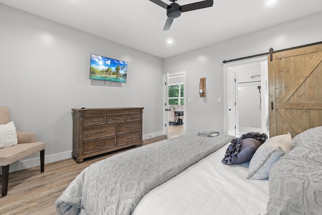 bedroom with light wood-style floors, baseboards, recessed lighting, a barn door, and connected bathroom