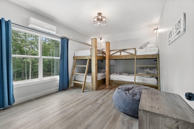 bedroom with a wall unit AC and wood finished floors