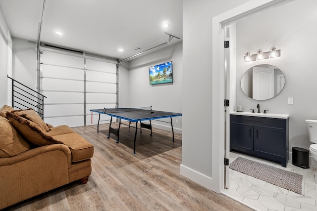 playroom featuring light wood-style flooring, a sink, baseboards, a garage, and recessed lighting