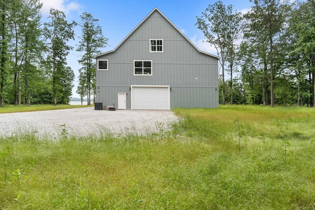 view of home's exterior with a detached garage, driveway, and cooling unit