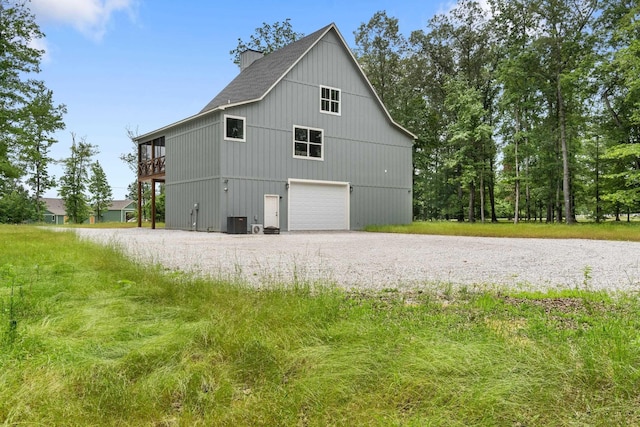 view of side of property with gravel driveway, a garage, central air condition unit, and roof with shingles