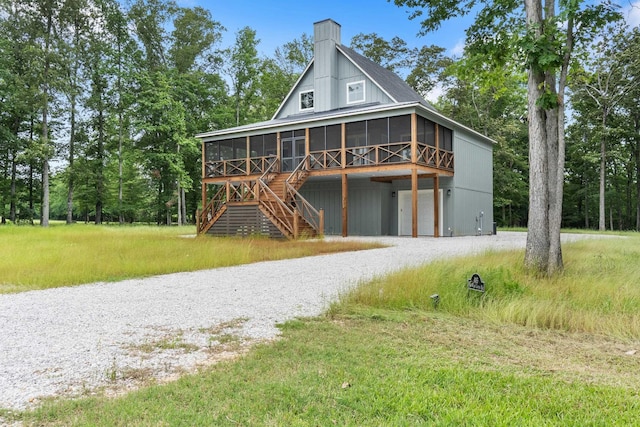 view of front of property featuring a sunroom, driveway, stairway, and a chimney