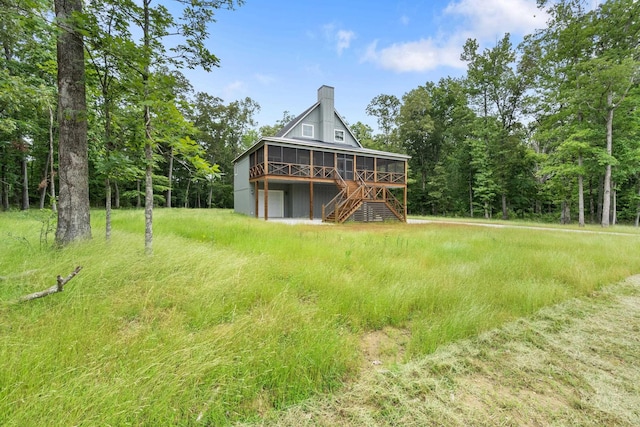 rear view of property with a sunroom, a chimney, and stairs
