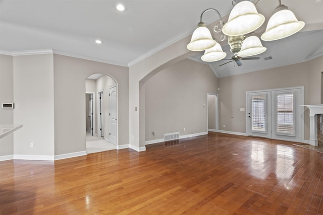 unfurnished living room featuring arched walkways, ceiling fan, wood finished floors, ornamental molding, and baseboards