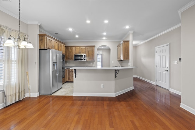 kitchen featuring appliances with stainless steel finishes, a chandelier, arched walkways, light wood-style flooring, and light countertops