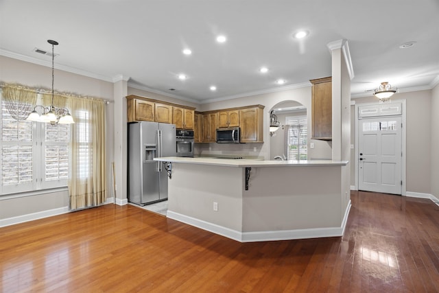 kitchen with stainless steel appliances, a chandelier, light countertops, arched walkways, and brown cabinets