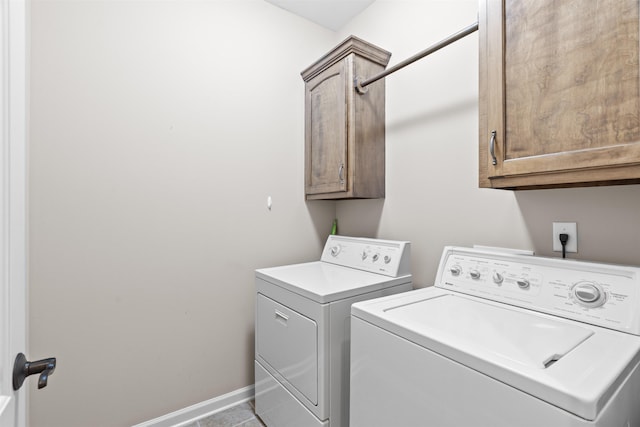 clothes washing area featuring cabinet space, washer and dryer, and baseboards