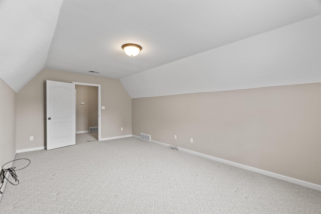 additional living space with light carpet, lofted ceiling, and baseboards