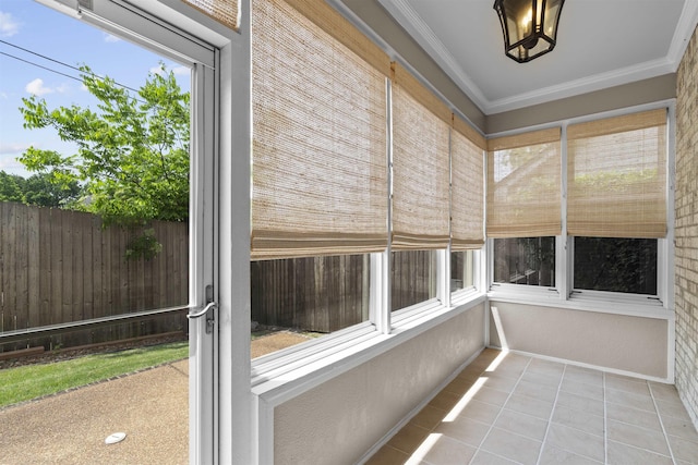 unfurnished sunroom featuring tile patterned flooring and crown molding