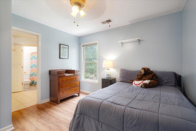 7733 Quick Fox Cv, Memphis, TN 38016 - bedroom with light wood-style flooring, a textured ceiling, a ceiling fan, connected bathroom, and baseboards