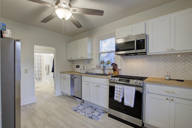 1975 Walker Ave, Memphis, TN 38104 - kitchen featuring stainless steel appliances, a sink, backsplash, a ceiling fan, and white cabinetry