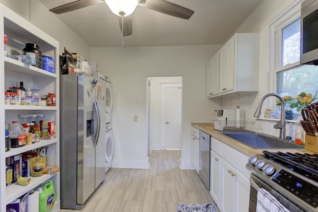 1975 Walker Ave, Memphis, TN 38104 - kitchen featuring appliances with stainless steel finishes, a sink, decorative backsplash, ceiling fan, and estacked washer and dryer