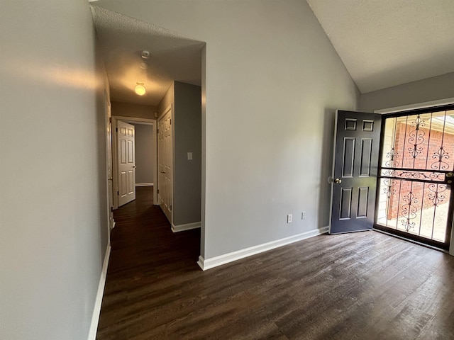 foyer with baseboards, dark wood-type flooring, and high vaulted ceiling