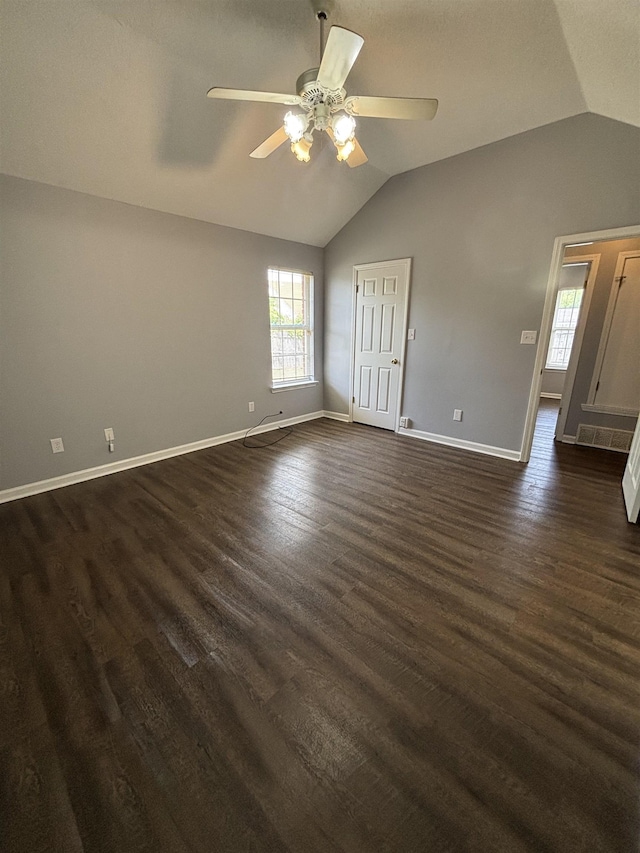 unfurnished room featuring lofted ceiling, healthy amount of natural light, a ceiling fan, baseboards, and dark wood-style flooring