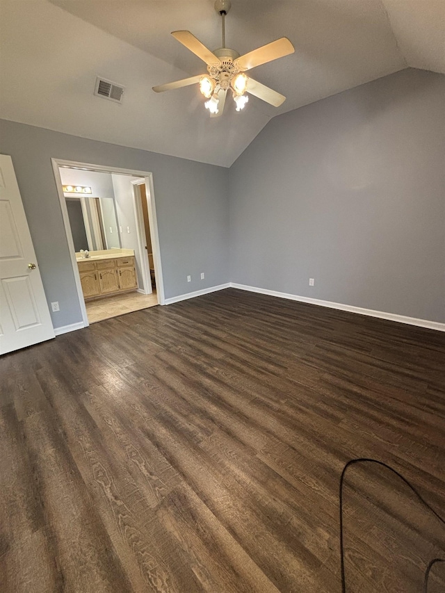 unfurnished bedroom with lofted ceiling, baseboards, dark wood-style floors, ensuite bath, and ceiling fan