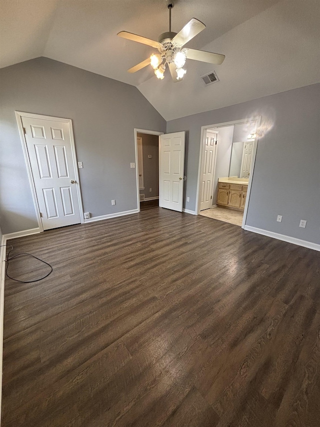 unfurnished bedroom featuring lofted ceiling, dark wood-type flooring, baseboards, connected bathroom, and a ceiling fan