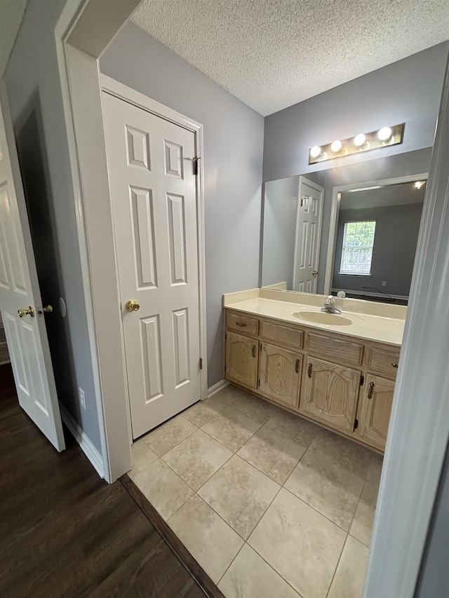 bathroom with vanity, a textured ceiling, wood finished floors, and baseboards