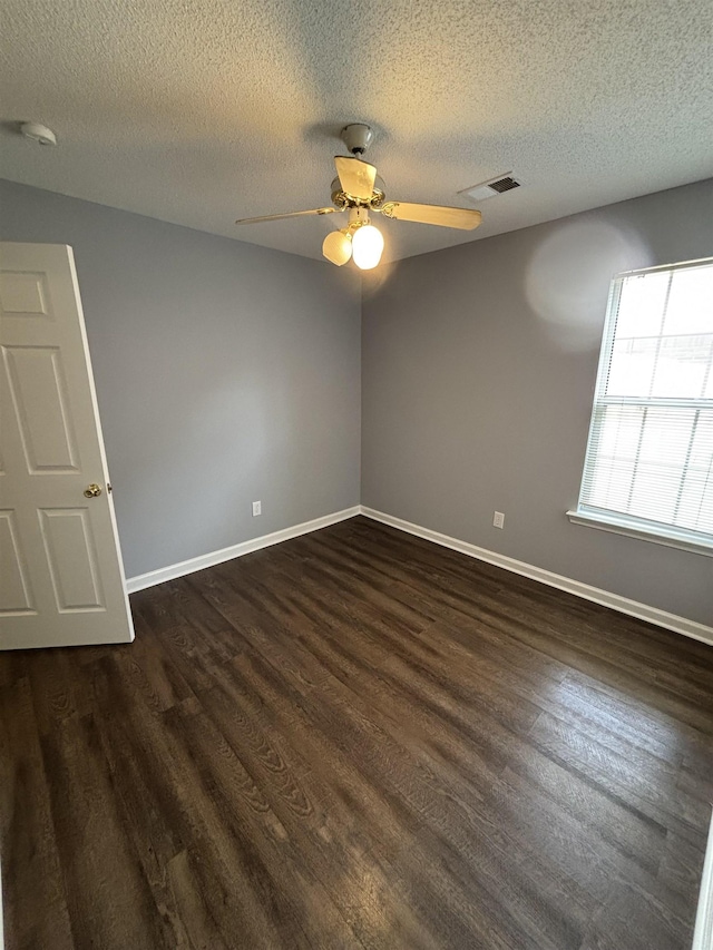 unfurnished room featuring dark wood-style flooring, ceiling fan, baseboards, and a textured ceiling