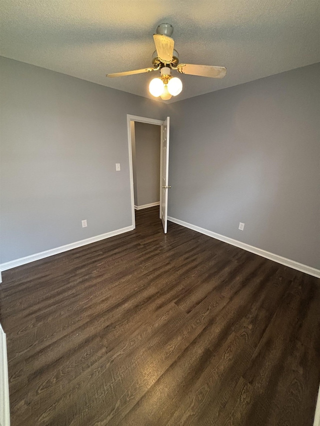 spare room with ceiling fan, dark wood-style flooring, baseboards, and a textured ceiling