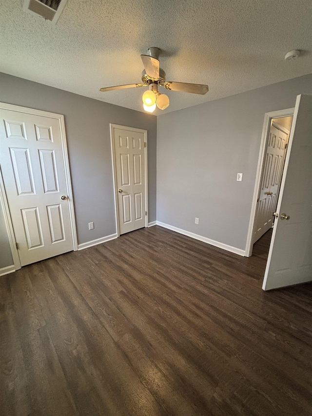 unfurnished bedroom with dark wood-style floors, baseboards, a textured ceiling, and a ceiling fan