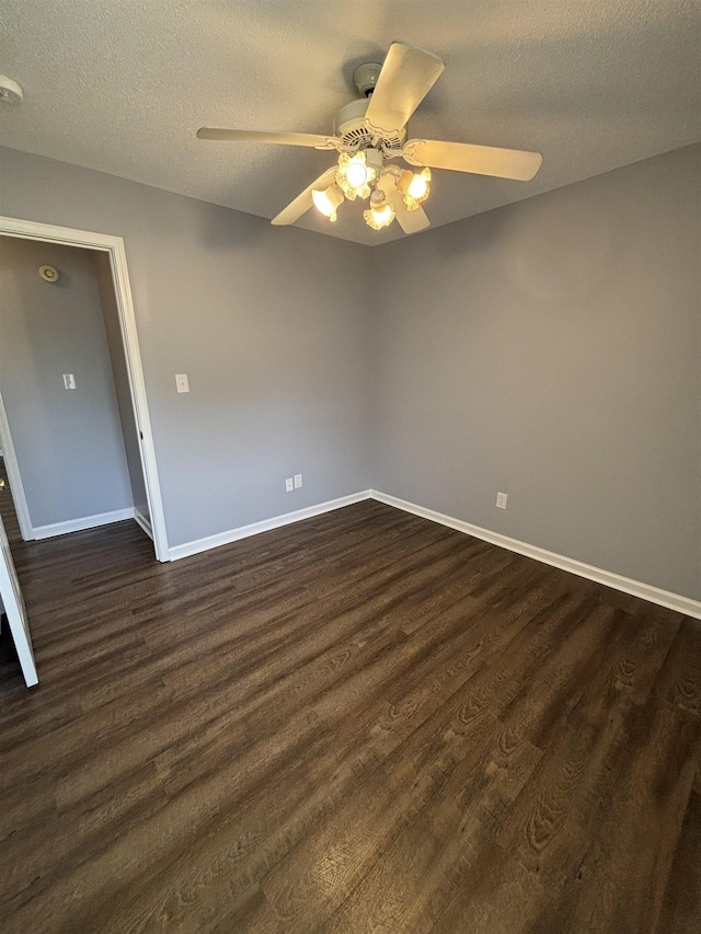 unfurnished room featuring a ceiling fan, dark wood-type flooring, a textured ceiling, and baseboards