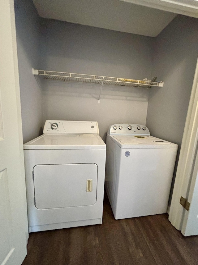 clothes washing area with washer and clothes dryer and dark wood-type flooring