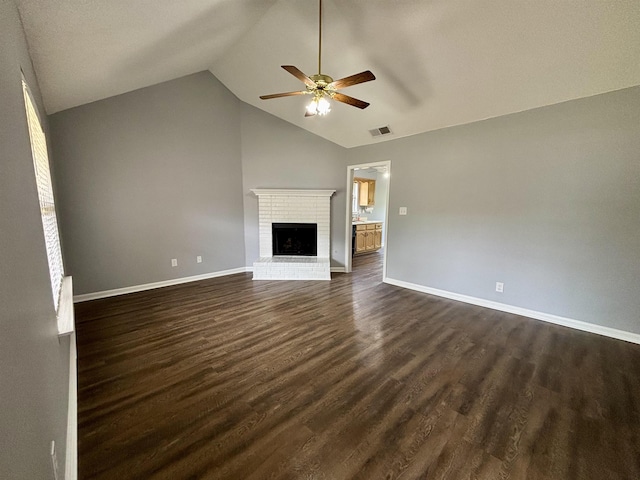unfurnished living room with ceiling fan, vaulted ceiling, dark wood finished floors, baseboards, and a fireplace