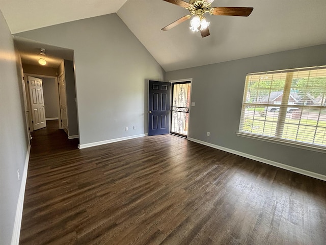 spare room featuring plenty of natural light, dark wood-type flooring, baseboards, and high vaulted ceiling