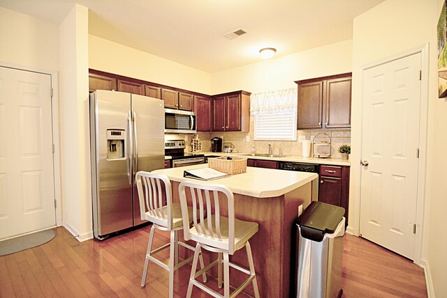 1342 Harbor Park Dr, Memphis, TN 38103 - kitchen featuring stainless steel appliances, light wood-type flooring, a breakfast bar, light countertops, and decorative backsplash