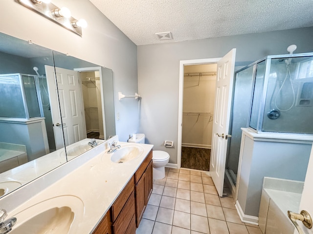 full bathroom with a stall shower, a textured ceiling, tile patterned floors, and double vanity
