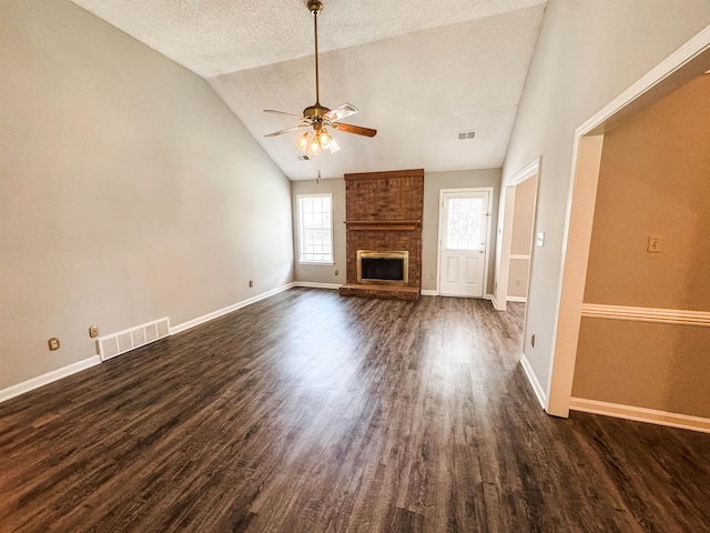 unfurnished living room featuring ceiling fan, dark wood finished floors, a brick fireplace, baseboards, and a textured ceiling