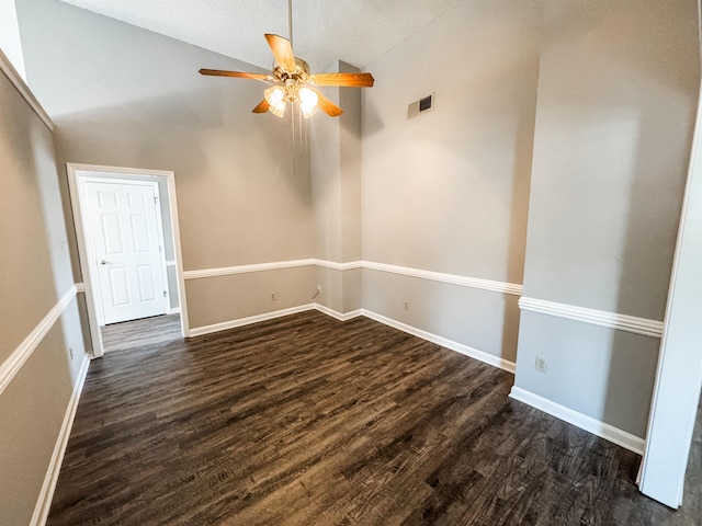 empty room with lofted ceiling, dark wood finished floors, a ceiling fan, and baseboards