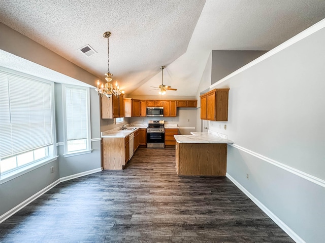 kitchen with appliances with stainless steel finishes, brown cabinetry, a textured ceiling, light countertops, and a chandelier