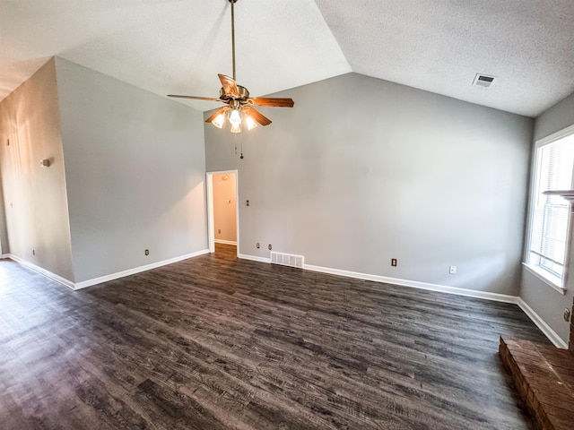 unfurnished living room with ceiling fan, vaulted ceiling, dark wood-style flooring, baseboards, and a textured ceiling