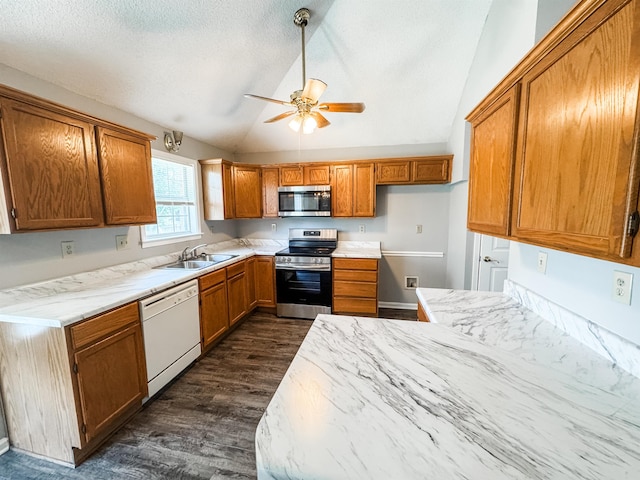 kitchen featuring stainless steel appliances, a sink, vaulted ceiling, dark wood-style flooring, and brown cabinets