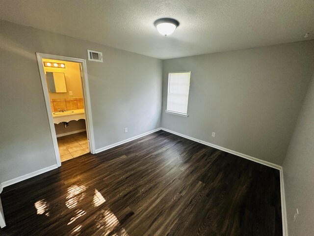2232 Amethyst Cv, Memphis, TN 38127 - unfurnished bedroom featuring a textured ceiling, dark wood-type flooring, baseboards, and ensuite bathroom